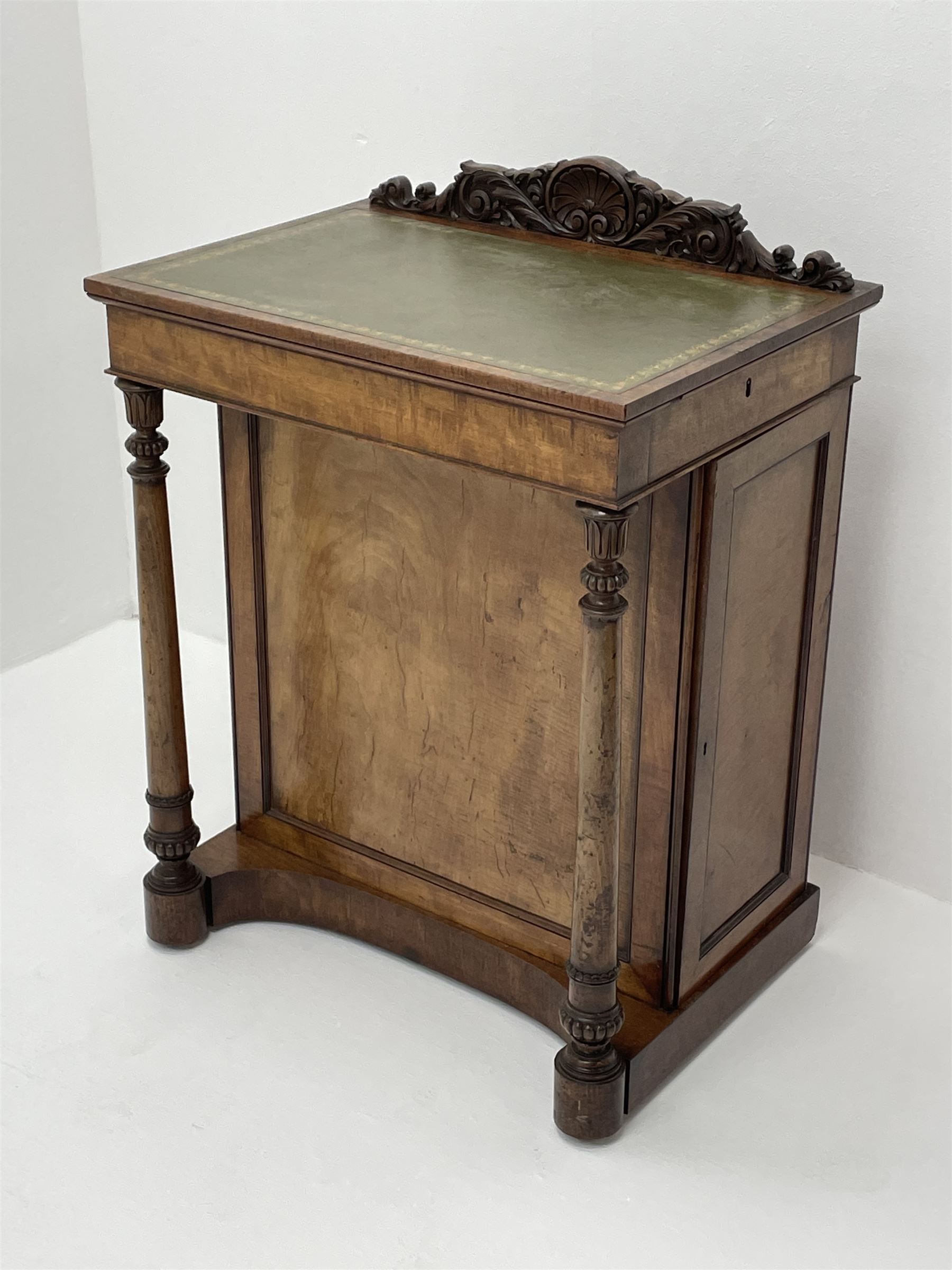 Early Victorian figured mahogany dressing cabinet, the raised shell and scroll carved back lifts to reveal rectangular easel mirror with mahogany band, flat rectangular top with tooled leather inset, slide at each side with matching leather inset, full width drawer above cupboard enclosing a series of five drawers, turned front supports, panelled front, sides and back