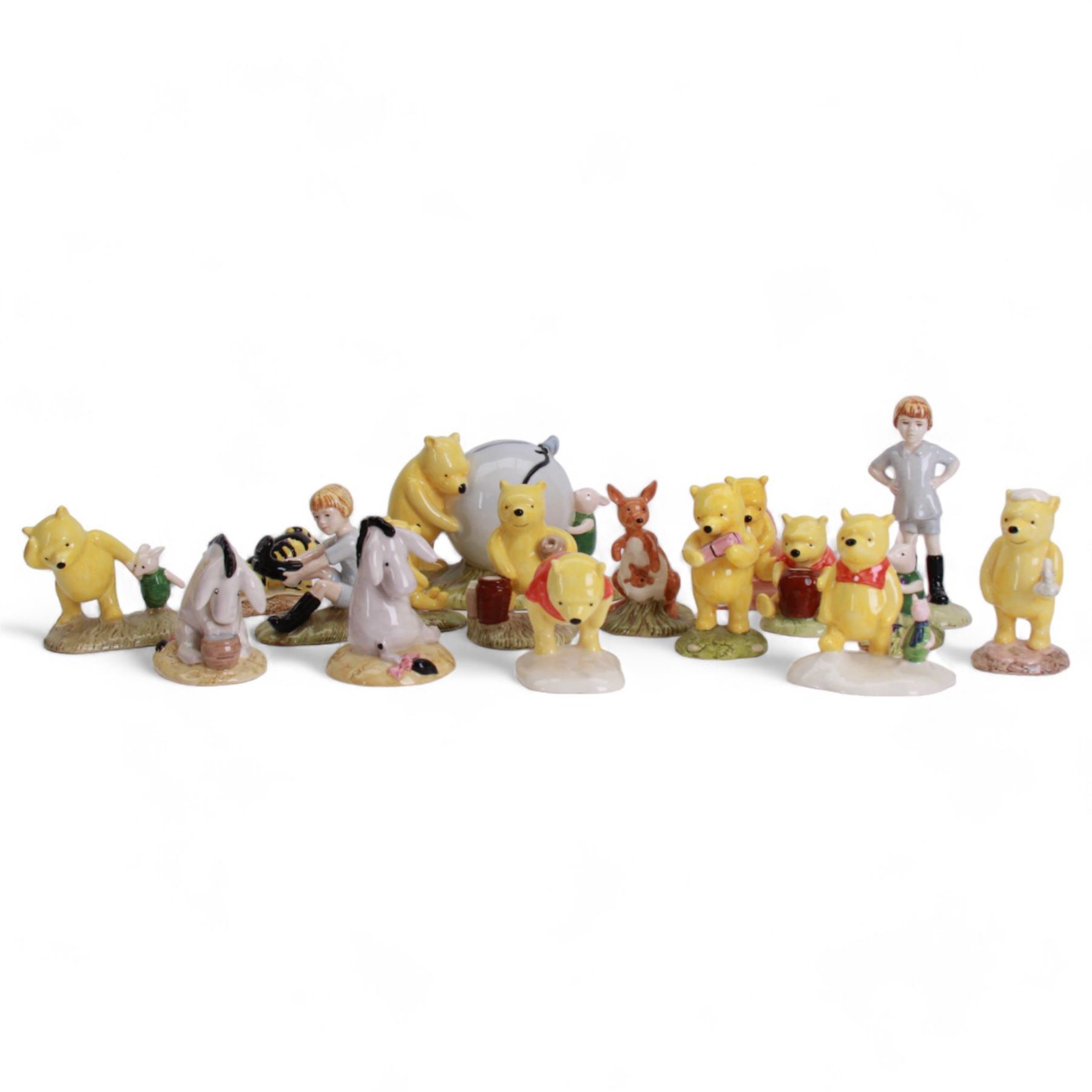 Sixteen Royal Doulton Winnie the Pooh figures, including Pooh's Blue Balloon money box, Winnie the Pooh in the Armchair, Piglet Picking Violets and Eeyore's Birthday etc, fifteen with boxes