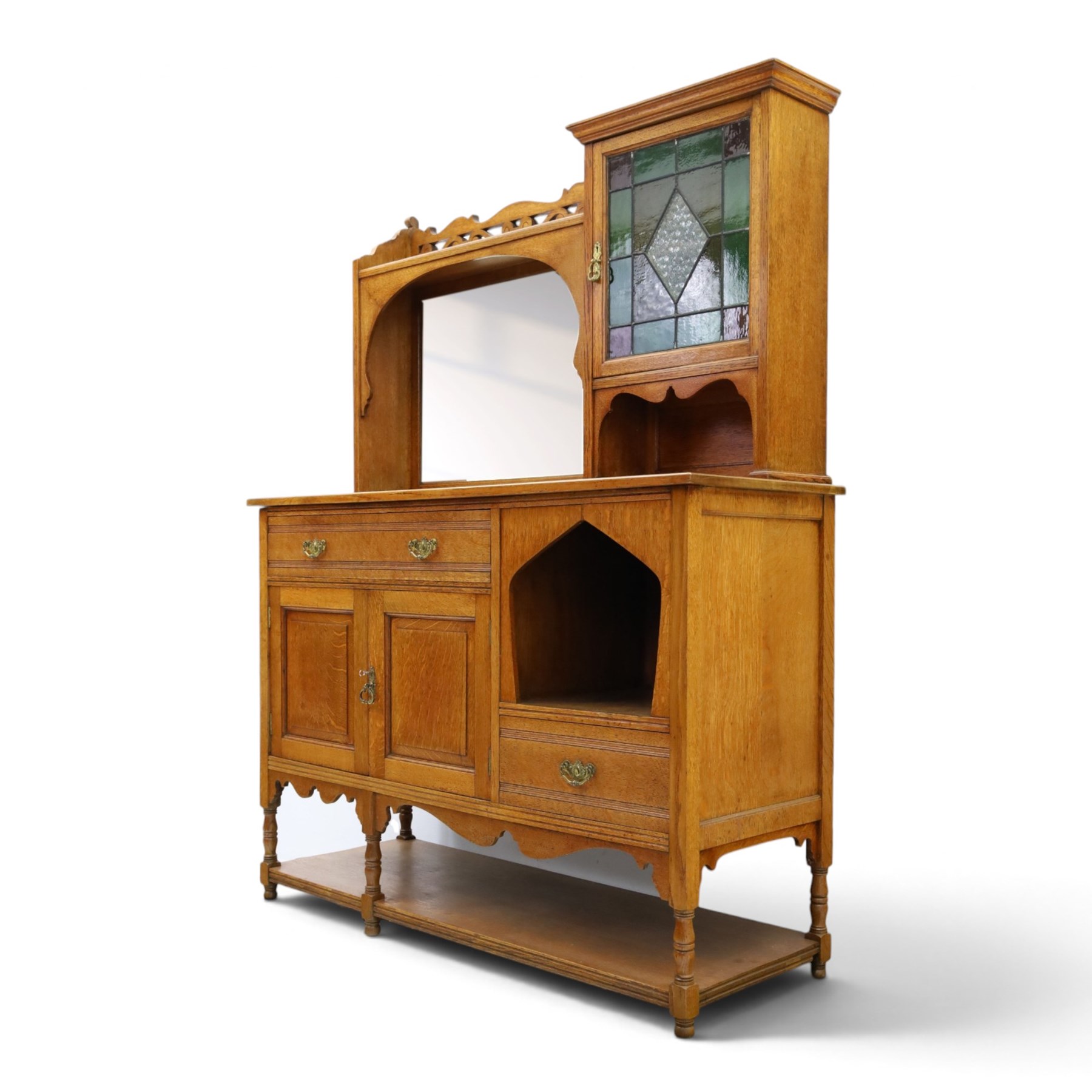 Maple & Co. - Arts & Crafts oak dresser with stained glass cupboard, raised section with pierced pediment above a mirrored back, with a stained glass fronted cupboard with fixed shelf, single long drawer, above a pair of fielded panels, with open recess above a short drawer, raised above a full length undertier with turned supports