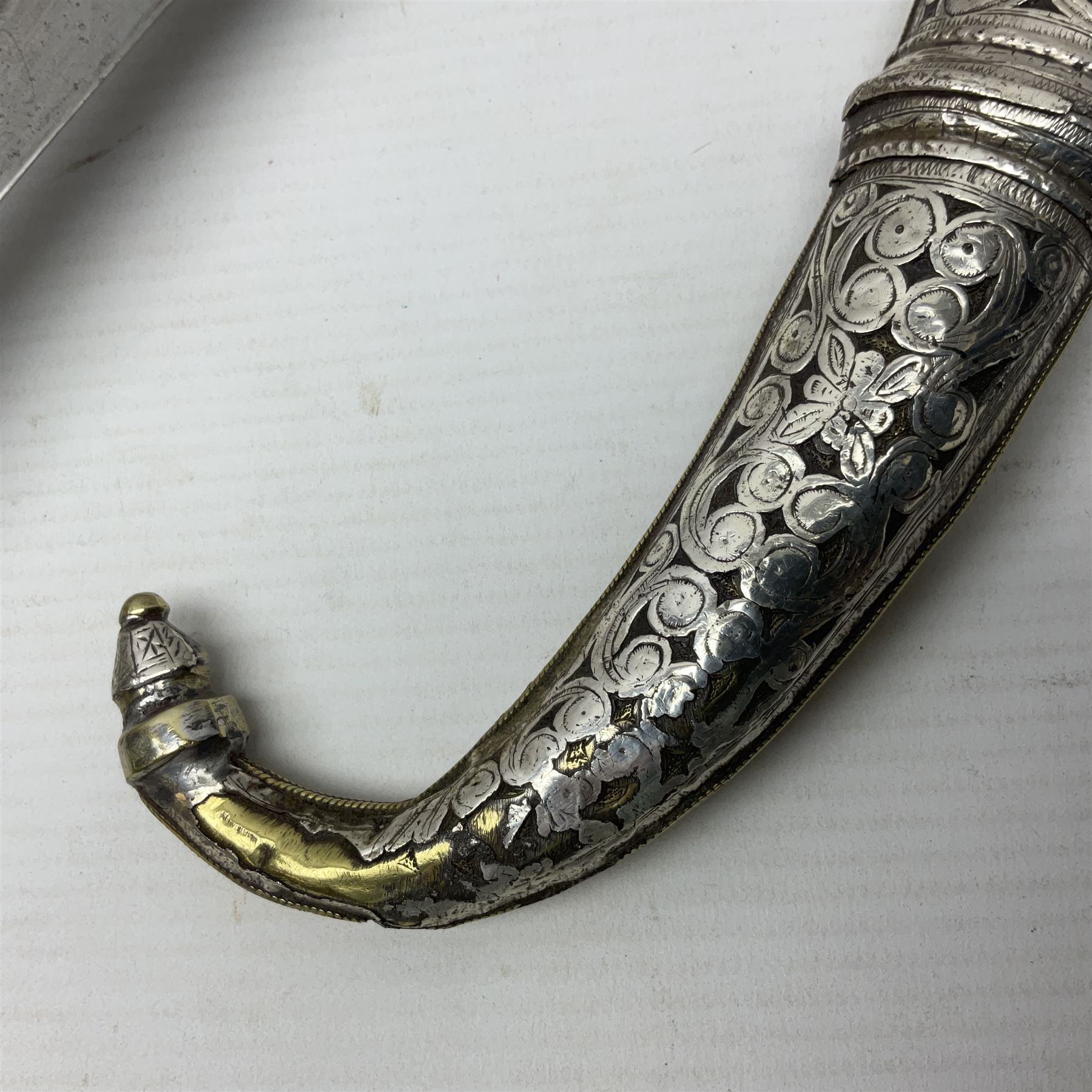 Moroccan jambiya dagger with 24.5cm plain curved blade stamped LONDON to the ricasso area, the hilt and scabbard overlaid with plain sheet brass to the back and ornate silver coloured metal to the front; waisted grip and arched pommel; two pyramid mounts to the scabbard L41cm overall; large billhook with curving blade and stacked leather washer grip; and a reproduction halberd blade (3)