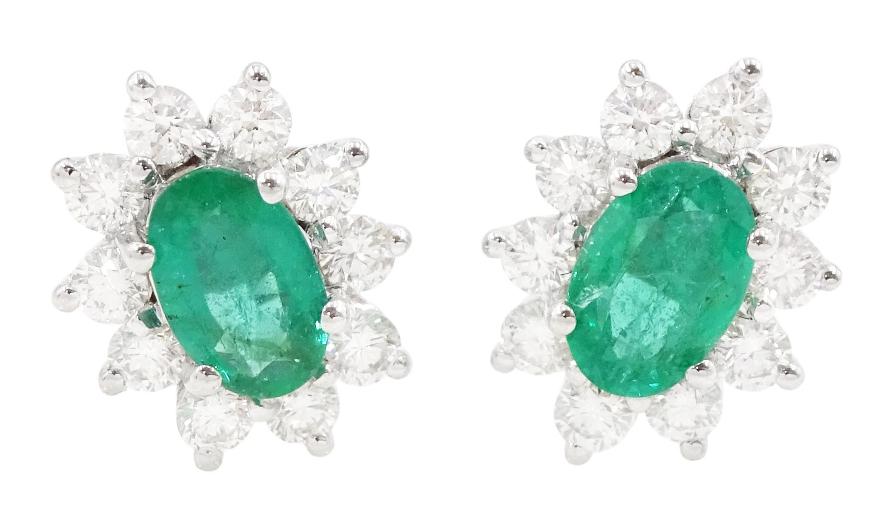 Pair of 18ct white gold emerald and diamond stud earrings, each cluster set with a single oval cut emerald surrounded by ten round brilliant cut diamonds, stamped, total emerald weight approx 0.80 carat, total diamond weight approx 0.55 carat