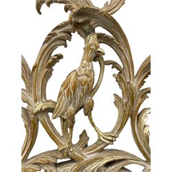 Oval wall mirror in carved and limed beech frame, the pediment carved with ho ho bird encased in interlaced foliate branch, decorated with flower heads and trailing bell flowers