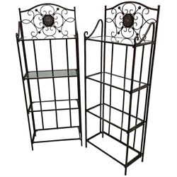 Pair of wrought metal conservatory plant stands, raised back with scrolling design, each fitted with three glass shelves