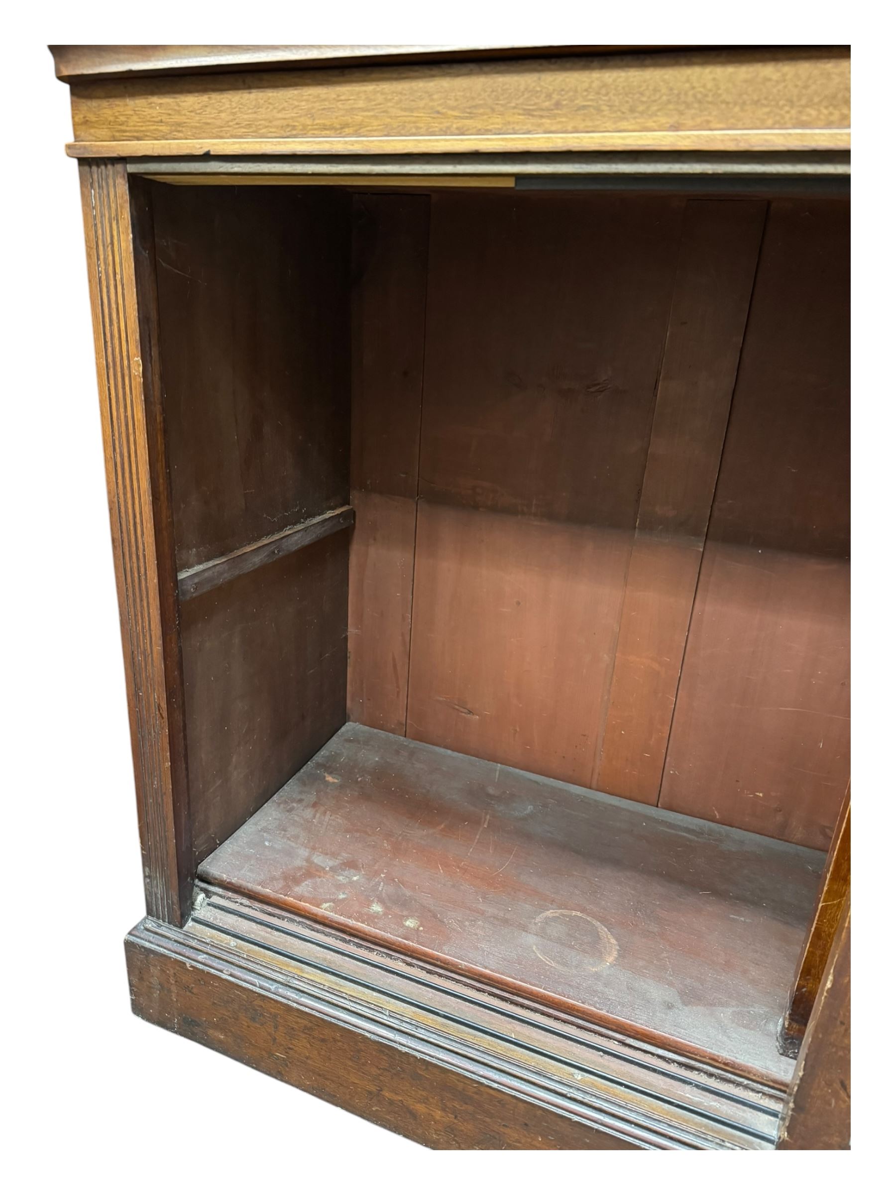 Early 19th century mahogany bookcase on cupboard, projecting cornice over four adjustable shelves, the cupboard enclosed by two sliding panelled doors, on moulded plinth base 