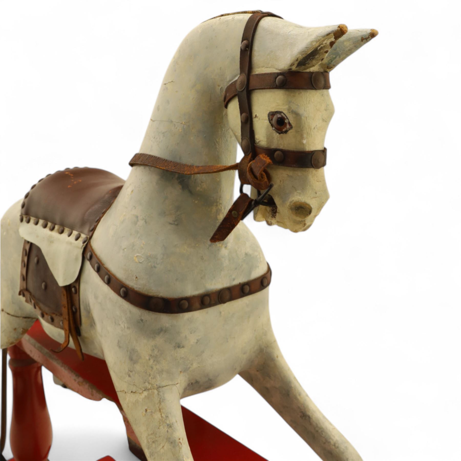 20th century carved and painted rocking horse, with original dappled paint finish, studded leather saddle and reins, on later red and black swing frame