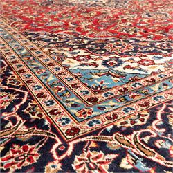 Persian Ardakan carpet, brick red field with ivory and navy central medallion, surrounded by stylised lotus blossoms and cloudband motifs, framed by rich indigo borders featuring palmettes, serrated leaves and angular vine work, woven in the city of Ardakan in central Iran