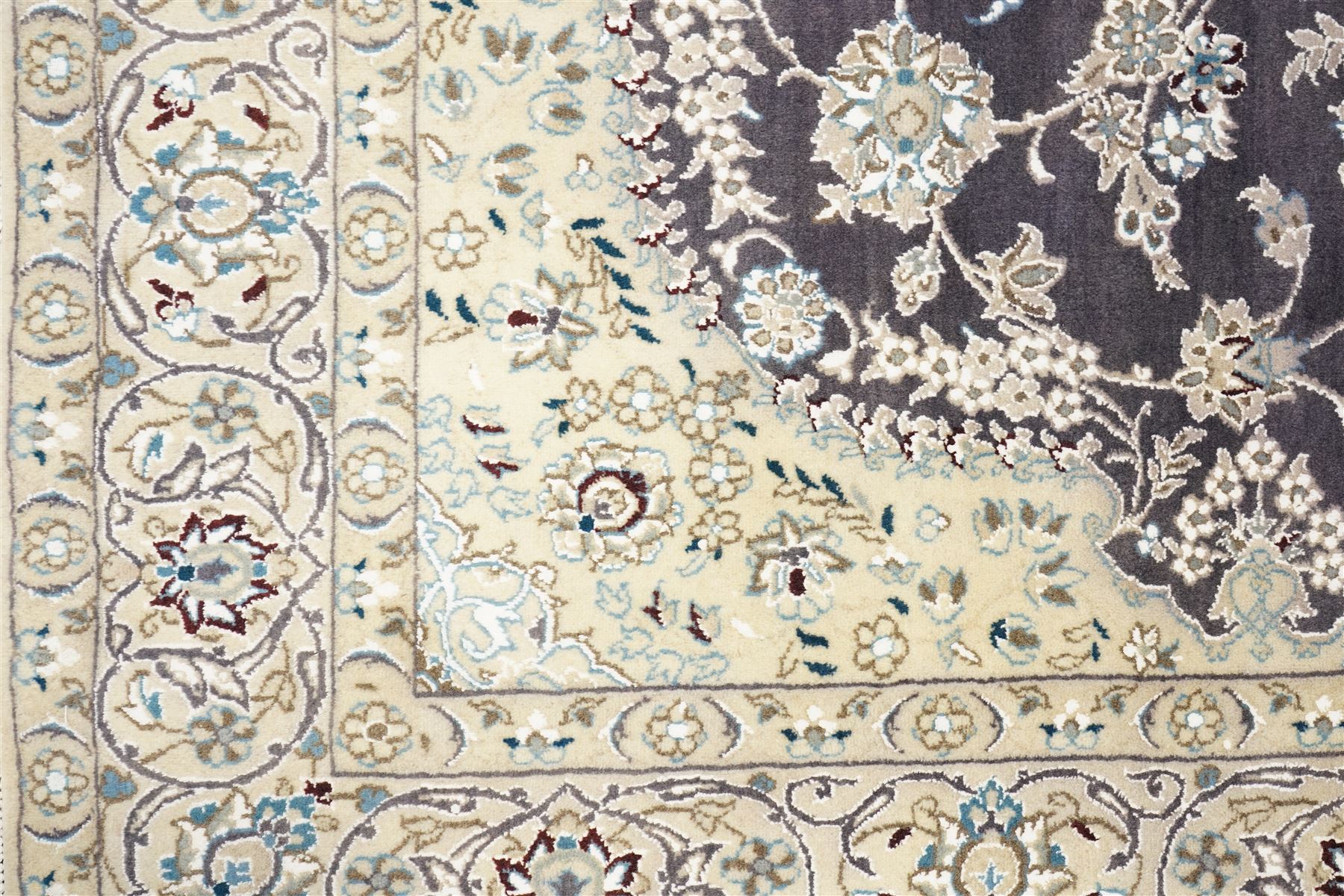 Central Persian Nain hand-knotted carpet, indigo field with central cusped medallion of radiating palmette form, enclosed with an elongated cartouche issuing network of scrolling vine work, arabesques and flowering sprays, surrounding ivory field of conforming design filled with foliate motifs and palmettes, spandrels of complimentary design with angular reserves, within principal border of ivory ground with scrolling vinery rosettes and arabesques, flanked by narrow guard stripes, with cotton fringe ends 