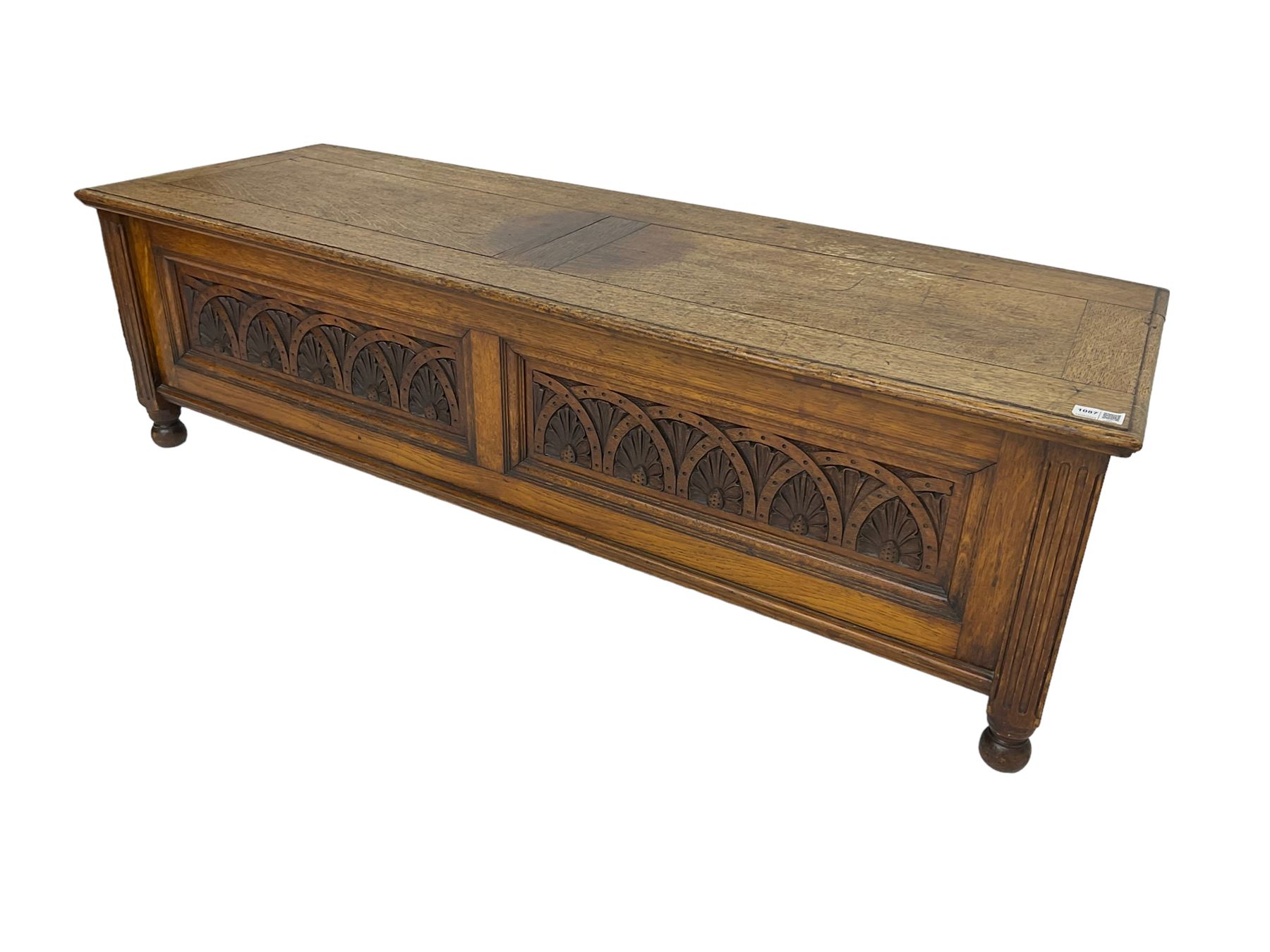 Early 20th century oak ‘bay window’ shaped blanket chest or coffer, hinged top, the front with two lunette carved panels flanked by fluted uprights, on turned feet
