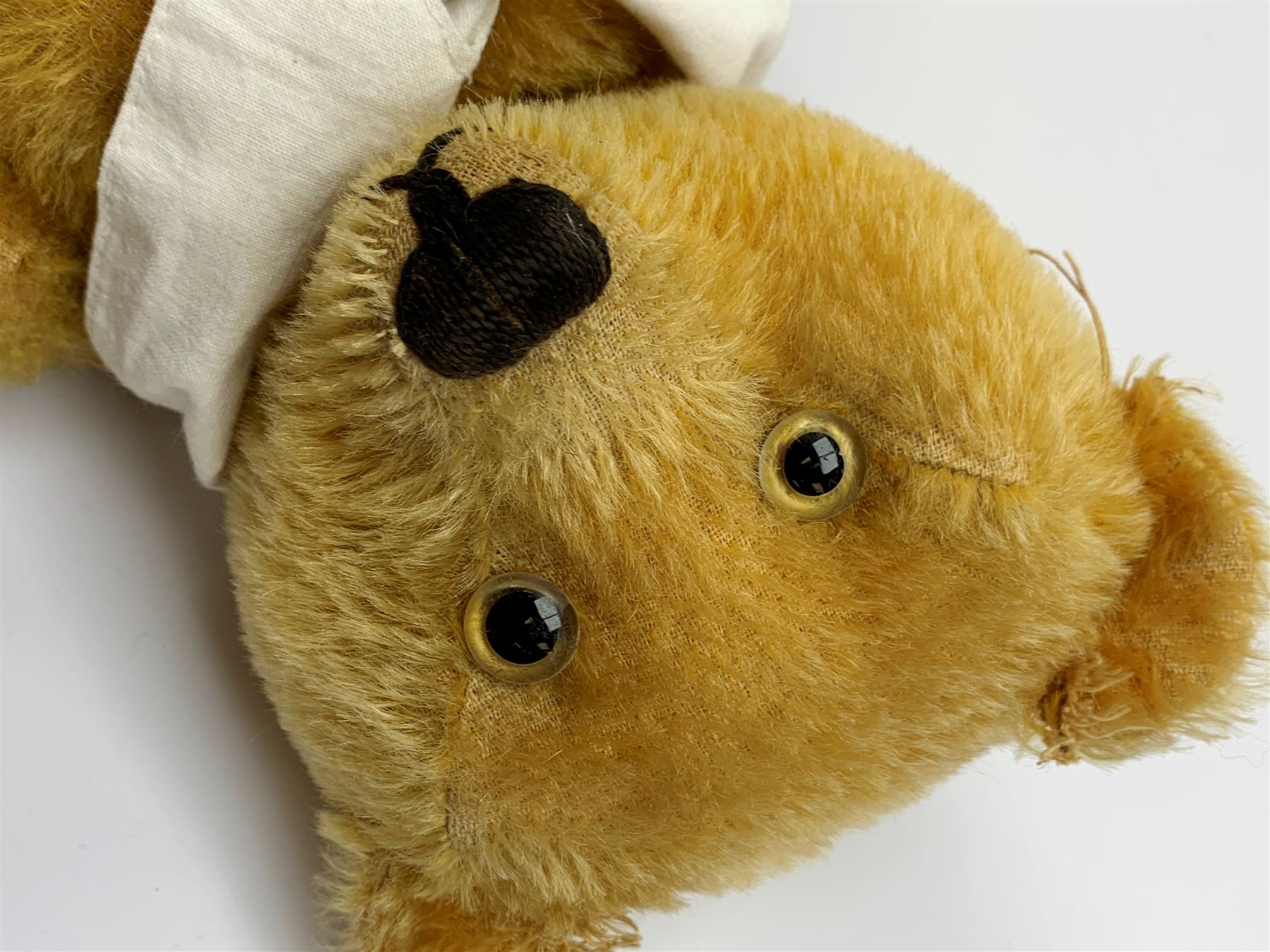Schuco 'yes-no' teddy bear c1925 with wood wool filled short golden mohair body, linen pads with stitched claws and  tail-operated moving head with glass eyes and vertically stitched nose and mouth H18