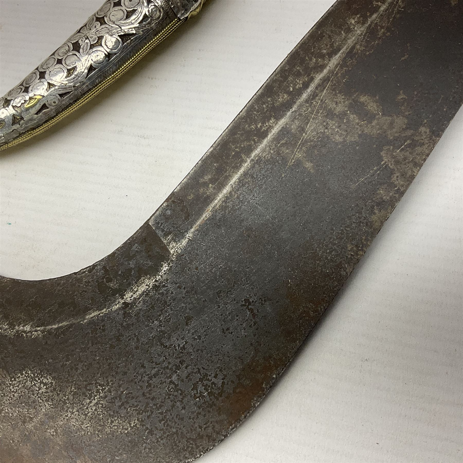 Moroccan jambiya dagger with 24.5cm plain curved blade stamped LONDON to the ricasso area, the hilt and scabbard overlaid with plain sheet brass to the back and ornate silver coloured metal to the front; waisted grip and arched pommel; two pyramid mounts to the scabbard L41cm overall; large billhook with curving blade and stacked leather washer grip; and a reproduction halberd blade (3)