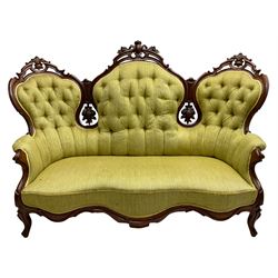 Victorian walnut settee, triple back with pierced and scroll-carved cresting rails over carved fruit and foliage decoration, upholstered in buttoned green fabric, serpentine seat and carved apron, on cabriole feet