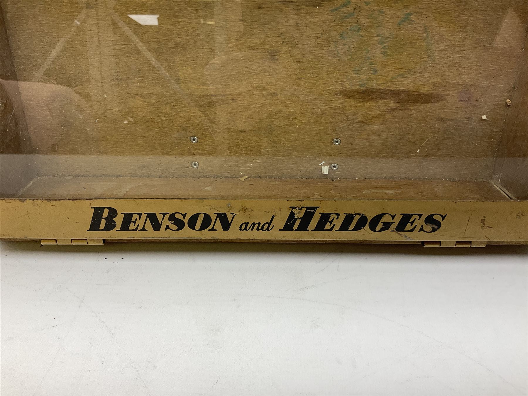 Benson and Hedges countertop glazed display cabinet, the glass hinged lid with white labelling of various cigarettes and cigars, the gilded metal bands with black lettering, W38cm D33cm H8cm
