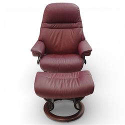 Ekornes - Stressless reclining armchair and matching footstool, upholstered in oxblood leather with padded headrest and segmented back cushion, shaped armrests with exposed adjustment handles, raised on stained laminated beech circular swivel base, the conforming stool on matching ring base
