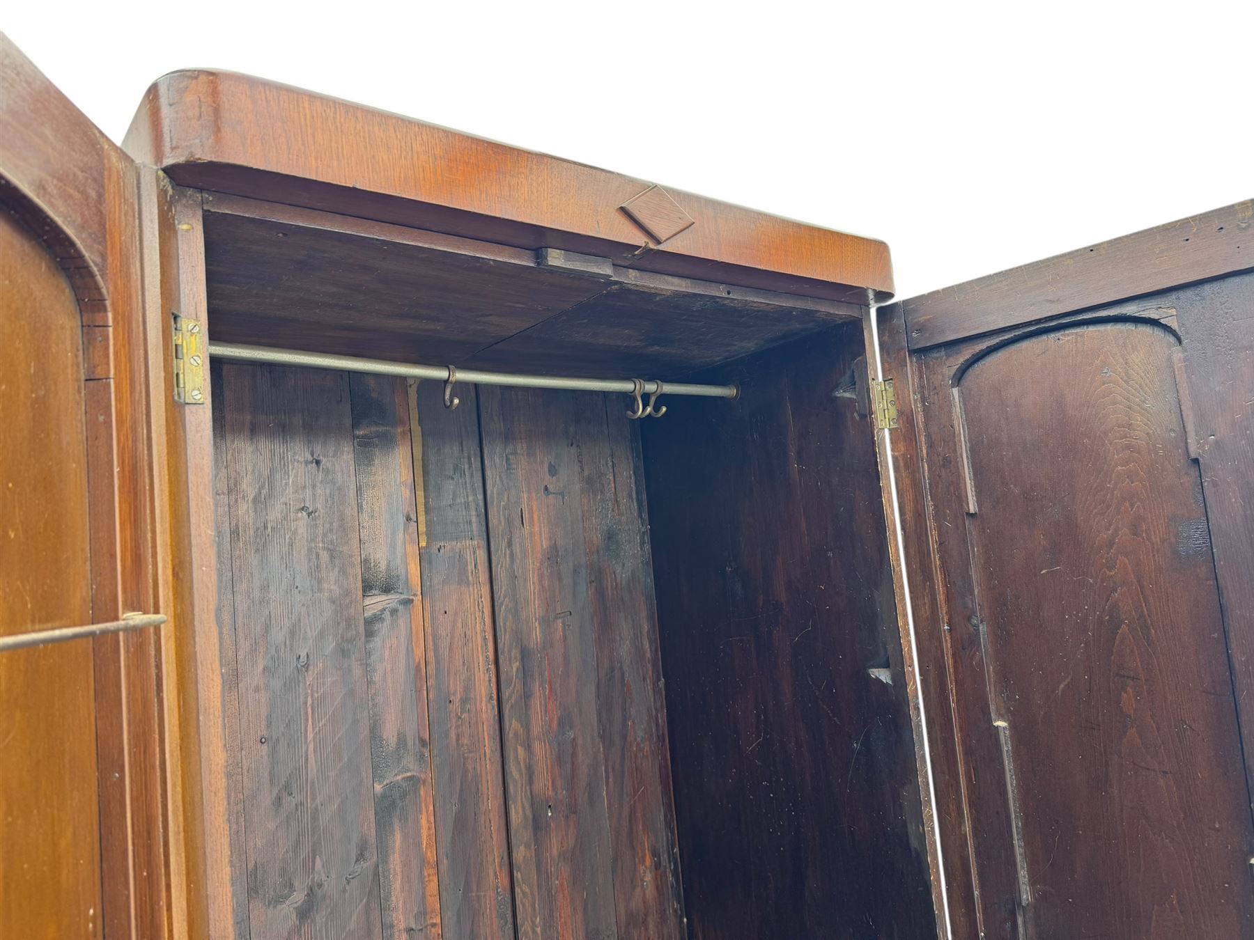 Victorian figured walnut single wardrobe, the moulded cornice with a central diamond motif over a pair of arched panelled doors with striking book-matched veneers, enclosing a fitted interior with hanging rail and hooks, on a plinth base