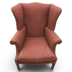 Georgian design wingback armchairs, the high backs flanked by shaped wings over padded scroll arms, upholstered in burgundy and gilt fleur-de-lys patterned fabric, loose cushion seats, raised on square tapering front supports