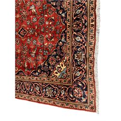 Persian Ardakan crimson ground rug, the field with shaped floral design medallion surrounded by curled leafy branches, scrolling border with stylised plant motifs