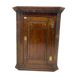 Georgian oak wall hanging corner cupboard, projecting dentil cornice over figured mahogany frieze and fielded panelled door, the interior fitted with three shaped shelves