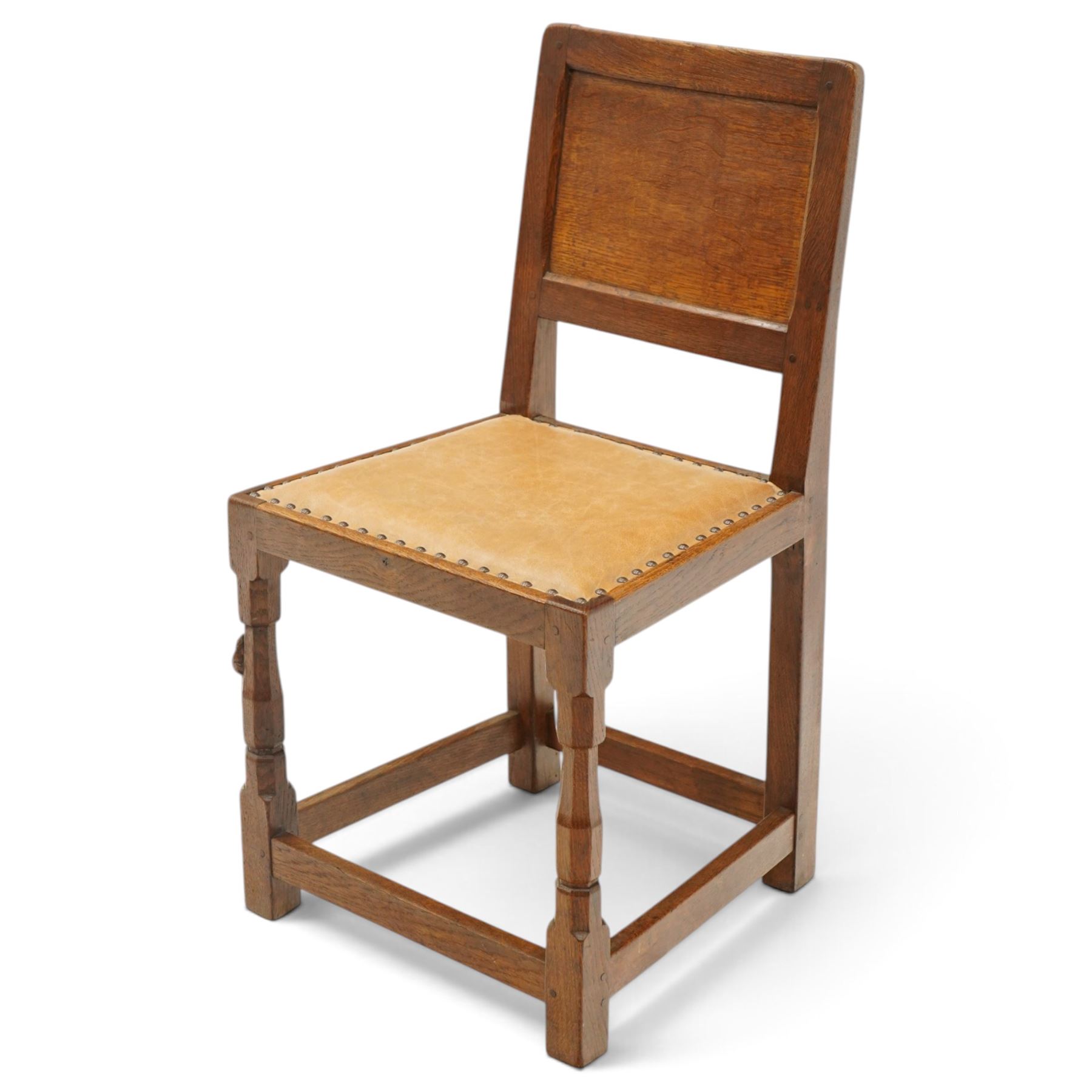 Mouseman side chair- panelled adzed back over tan leather upholstered seat with studwork, on octagonal front supports united by stretchers, each with signature carved mouse, by the workshop of Robert Thompson, Kilburn