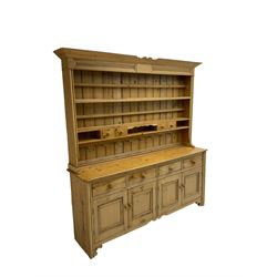 Traditional rustic pine dresser, projecting cornice over three-tier plate rack and space drawers, fitted with four drawers over four panelled cupboard doors