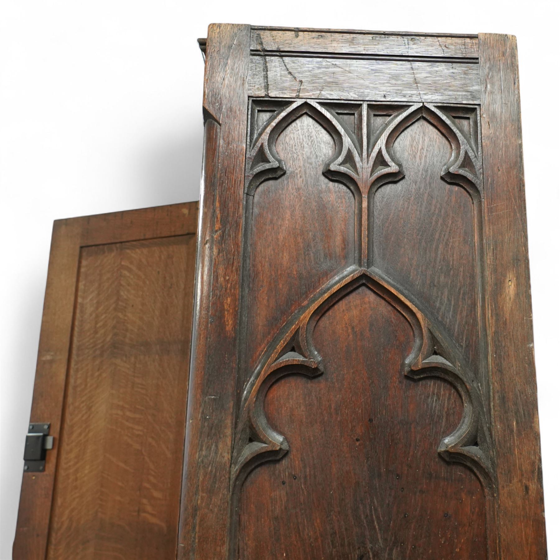 19th century Gothic Revival oak Sacristy vestment cupboard of tall proportions, fitted with two ecclesiastical trefoil moulded panelled doors enclosing four shelves, flanked by a chamfered corner, the side panelled and moulded with matching sacristic architectural mouldings, on skirted base
