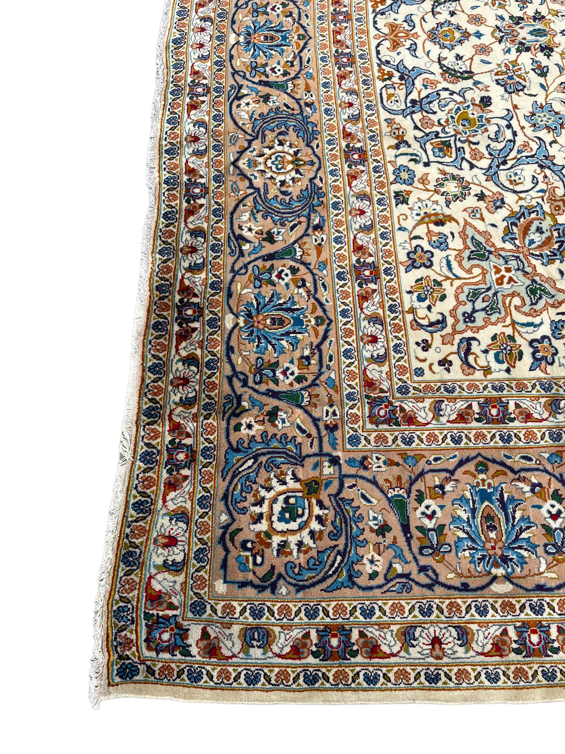Persian Kashan ivory ground carpet, the interlaced foliate medallion surrounded by trailing plant motifs interlaced with scrolls, the guarded border with repeating stylised flower heads
