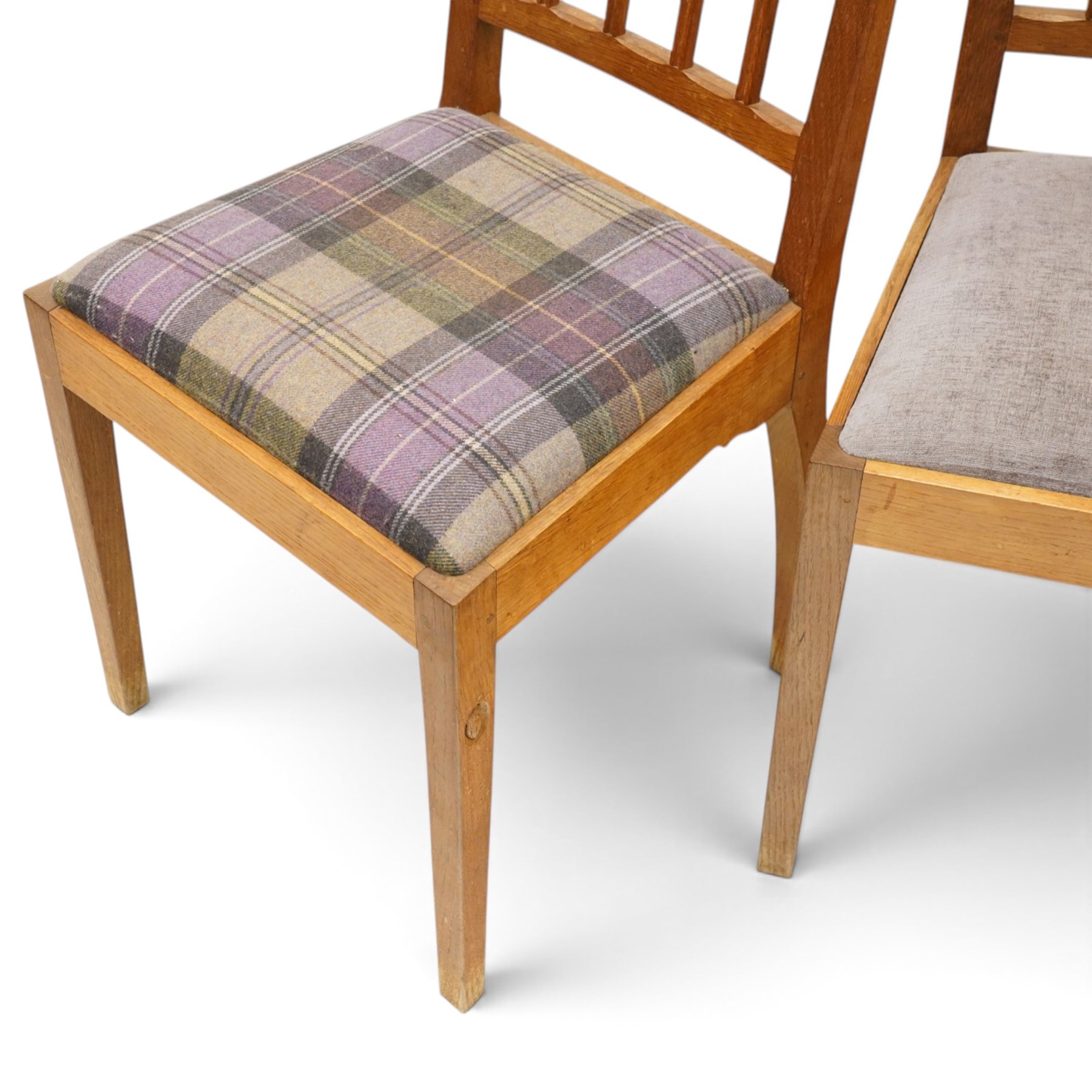 Acorn Industries - set of eight oak dining chairs, the shaped cresting rail over a fluted stick back, the drop-in seats upholstered in contrasting form with four pale mauve and four in purple tartan, raised on square supports, carved with acorn signature, by Alan Grainger, Brandsby