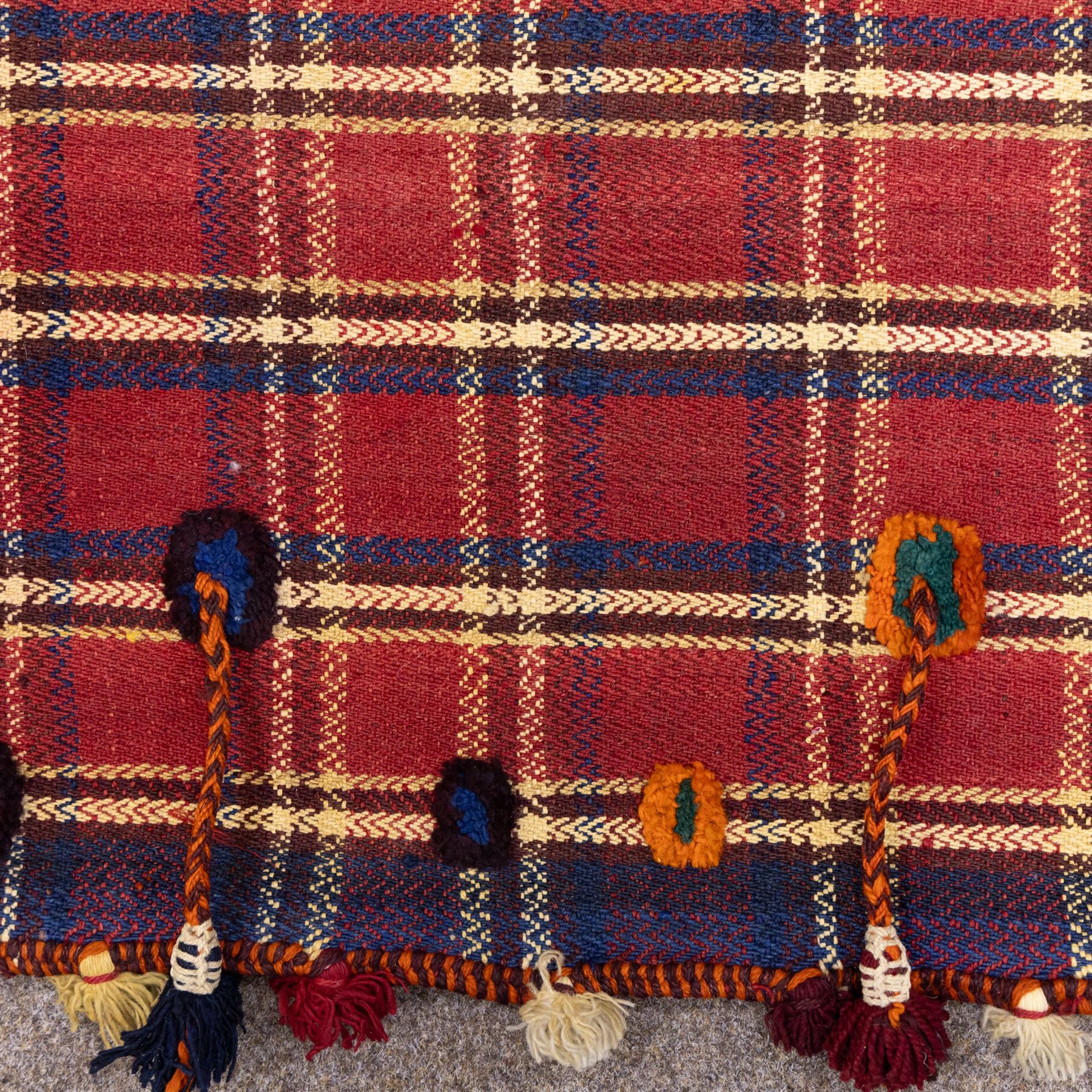 South West Persian Jajim kilim flatweave runner, composed of joined narrow woven bands,  field decorated with checked and striped motifs in shades of madder red, indigo, ivory ochre, and green, sides applied knotted wool tufts and braided elements with tasselled edges, (due to the large size, the runner is illustrated in two sections) 