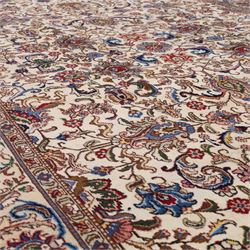 North West Persian Tabriz, hand-knotted carpet, ivory ground with dense scrolling vine-work, palmettes, flowering sprays, and stylized leaves framed by a principal border of scrolling floral motifs and palmettes and flanked by narrow guard borders, with cotton fringe ends