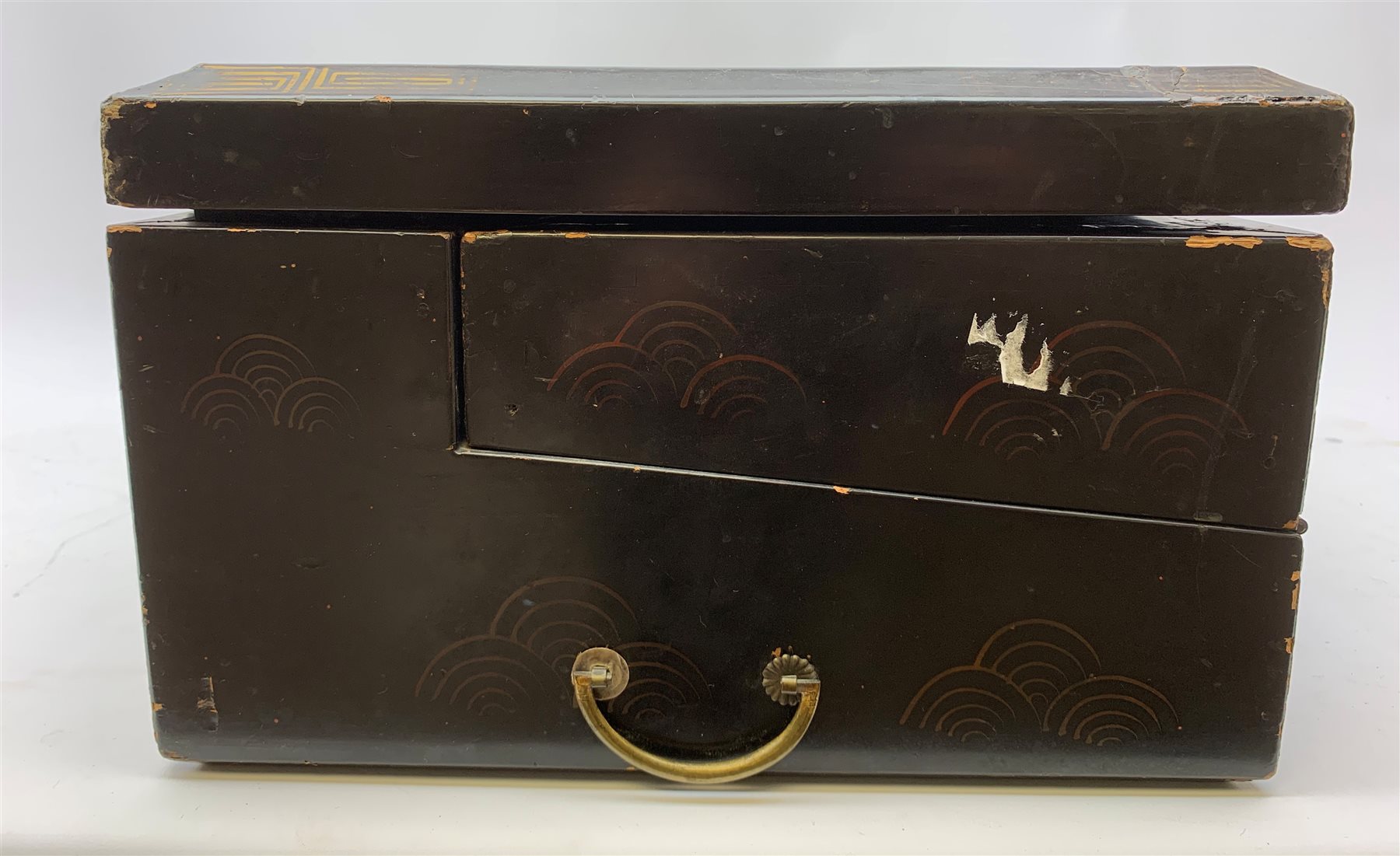  A 20th century Chinese black lacquer and gilt detailed writing box, decorated with figures, pagodas and cranes amidst a mountainous landscape, the hinged cover opening to reveal a compartmented interior and fold out baize lined slope, H20cm L46.5cm D31.5cm.   