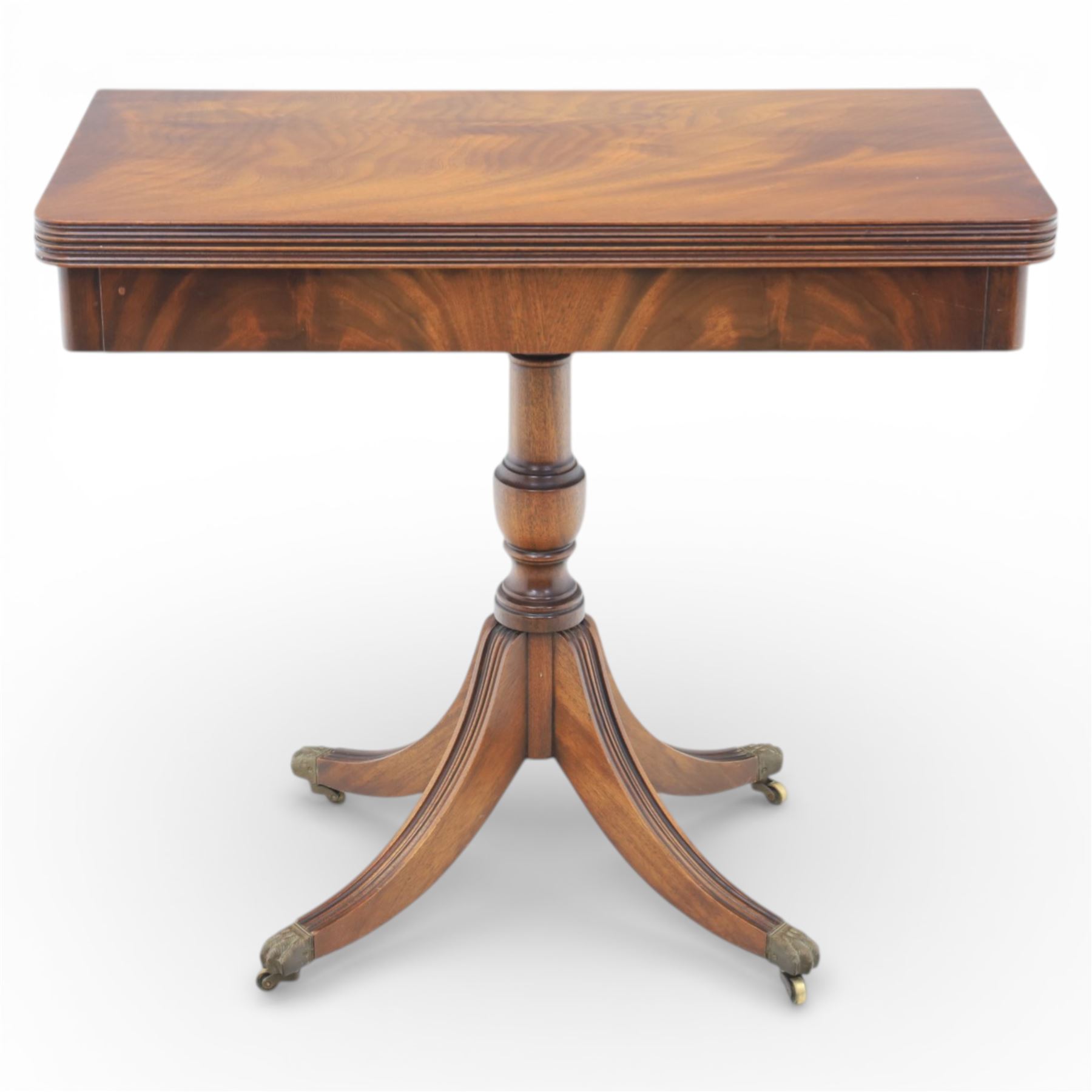 Victorian design mahogany card table, rectangular top with swivel and fold open action, revealing a baized lined interior, raised on turned baluster column, with reeded legs terminating in brass paw castors 