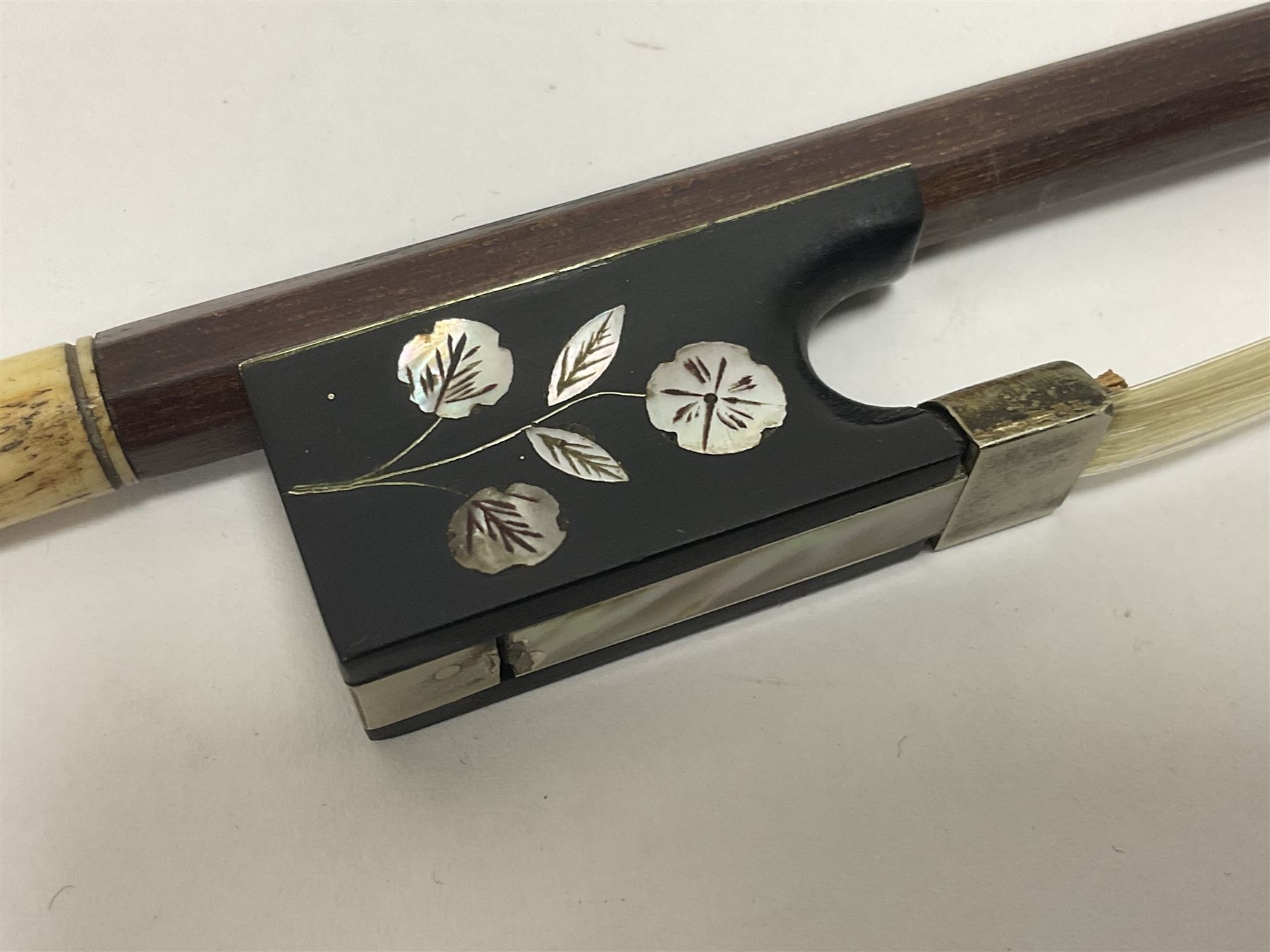 19th century wooden violin bow with a decorative mother of pearl inlay depicting flowers to the frog, with a bone adjuster screw