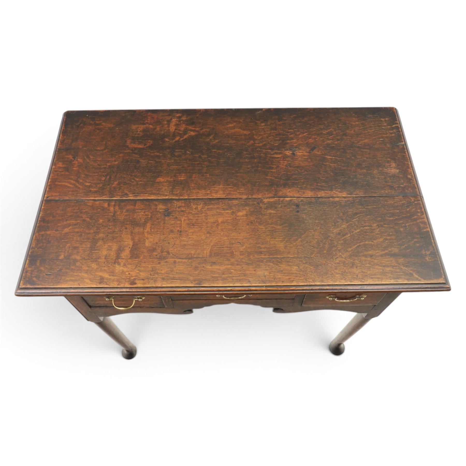 18th century oak lowboy, rectangular plank top with moulded edge, above three assorted drawers with brass swan neck handles, shaped apron raised on pad feet
