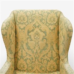 George III wing back armchair, the tall upholstered back with deep wings and gently shaped outline, padded arms flowing into the seat, loose cushion seat upholstered in a foliate patterned fabric, standing on square legs joined by stretchers