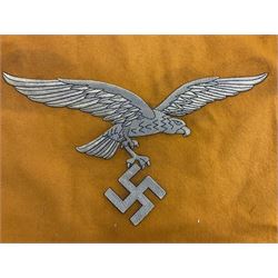 Two replica German Luftwaffe trumpet banners, one heavily silver wire embroidered with Luftwaffe eagle in a wreath, on an amber, white and black rayed background, , with silver wire tasselled border and four leather hanging loops, approx. 50 x 49cm; the other slightly larger heavily gold wire embroidered with the Luftwaffe eagle on a plain amber ground with gold wire tasselled border and two hanging loops (2)