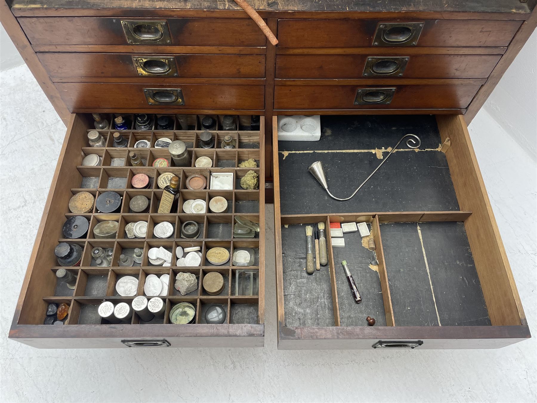 Edwardian mahogany artist's cabinet once belonging to the British artist Eli Marsden Wilson (1877-1965), raised panelled back mounted by carved brackets, sloped and hinged glazed lid enclosing paint holders and compartments, up-and-over panelled door revealing three slides, fitted with two banks of five graduating drawers with recessed brass handles, on skirted base.

Together with a quantity of artists' equipment and tools including paints, paintbrushes, charcoal, chalks, etc. and various prints relating to the life of the artist, including Quaker anti-war posters, Victorian Stevengraphs, and various chromolithographs 

Provenance: Removed from the studio of Eli Marsden Wilson. The cabinet comes to us for sale through family descent. The vendor is descendant of Marsden. Many further etchings removed from the cabinet are being sold in the Spring Art Sale, Friday 15th March 2024, Lots 265-271.

Notes: born in Ossett, Eli Marsden Wilson was the only son of Alfred Wilson, a foreman beamer, and Emma Marsden, and had five sisters. After studying at Wakefield College of Art, he moved to the Royal College of Art in London, where he became a pupil of Sir Frank Short. He had his first exhibit at the Royal Academy in 1905, the same year he married fellow artist Hilda Mary Pemberton.

A Quaker, vegetarian, and pacifist, he was a conscientious objector in World War I and as such was imprisoned in 1917 for two years. In September 1922 he was commissioned by Princess Marie Louise to produce miniature etchings for Queen Mary's Dolls' House at Windsor Castle; two such etchings are being sold in the Spring Art Sale, Friday 15th March 2024, Lot 265.