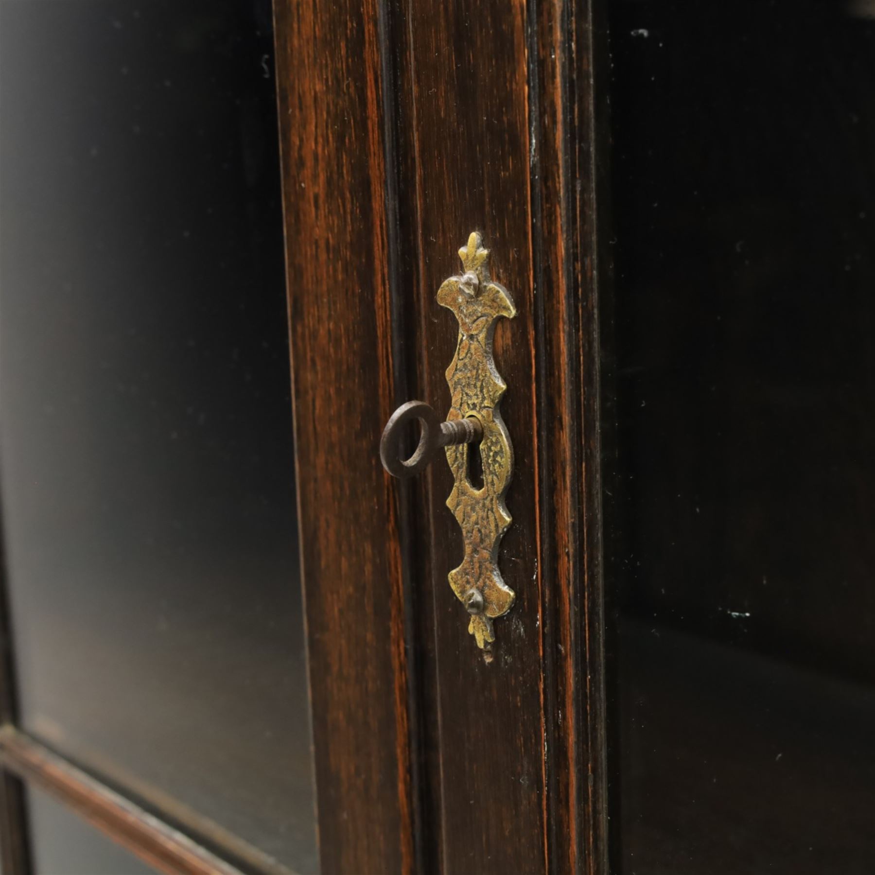 Early 20th century Jacobean Revival dark stained oak dresser, the associated upper section enclosed by twin glazed doors with shaped moulded glazing bars, over separate base fitted with two drawers, raised on bobbin turned legs