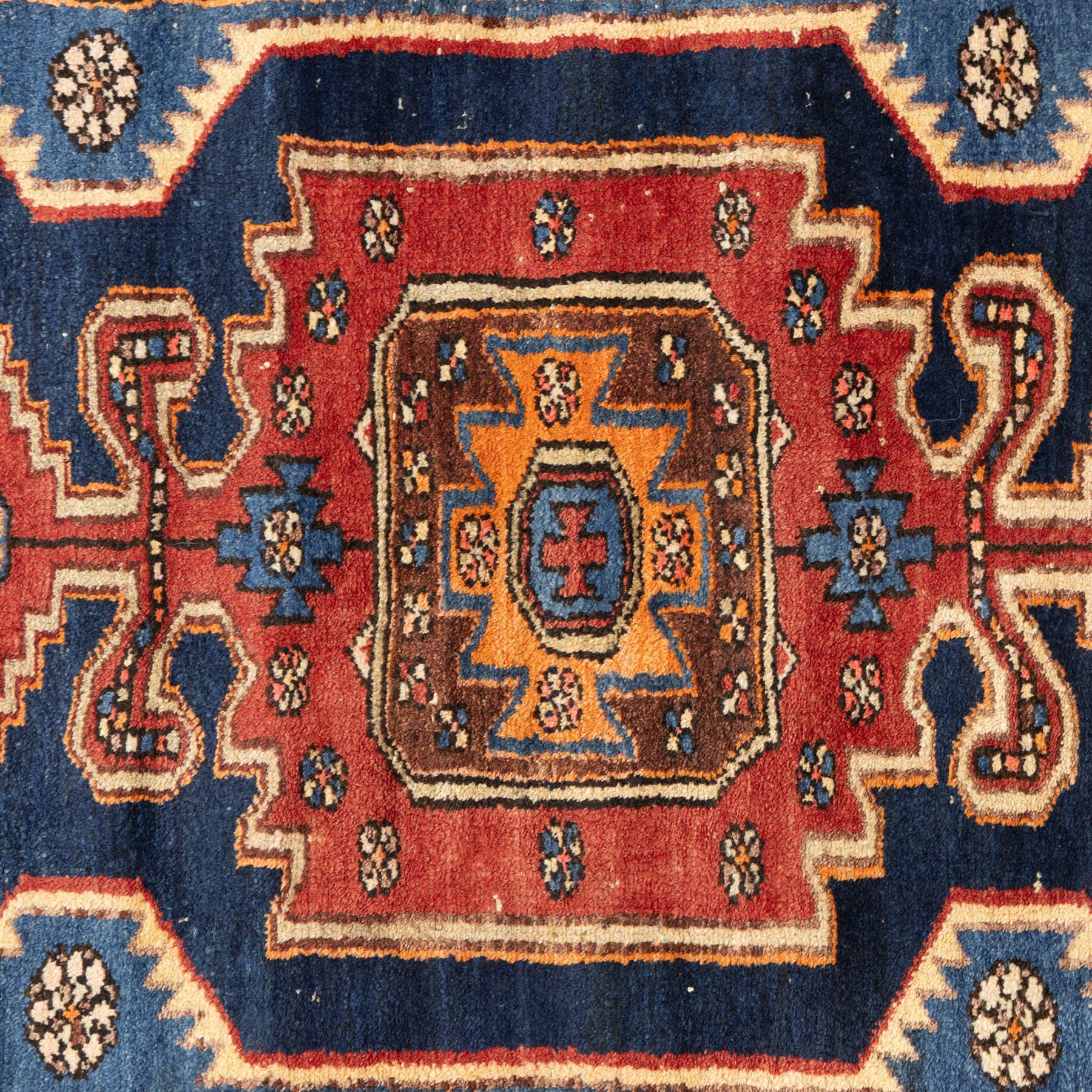 Persian Qashqai rug, wool on cotton foundation, triple stepped lozenge medallions with stylised motifs on a blue ground, within floral and geometric borders in rich red and cream

