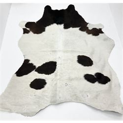 Dark brown and white patterned cow hide rug, L183cm W140cm.