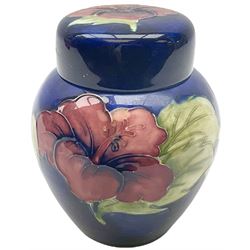Moorcroft ginger jar, decorated in the Hibiscus pattern upon a blue ground, with paper label beneath detailed 'Potters to the late Queen Mary', H11cm.