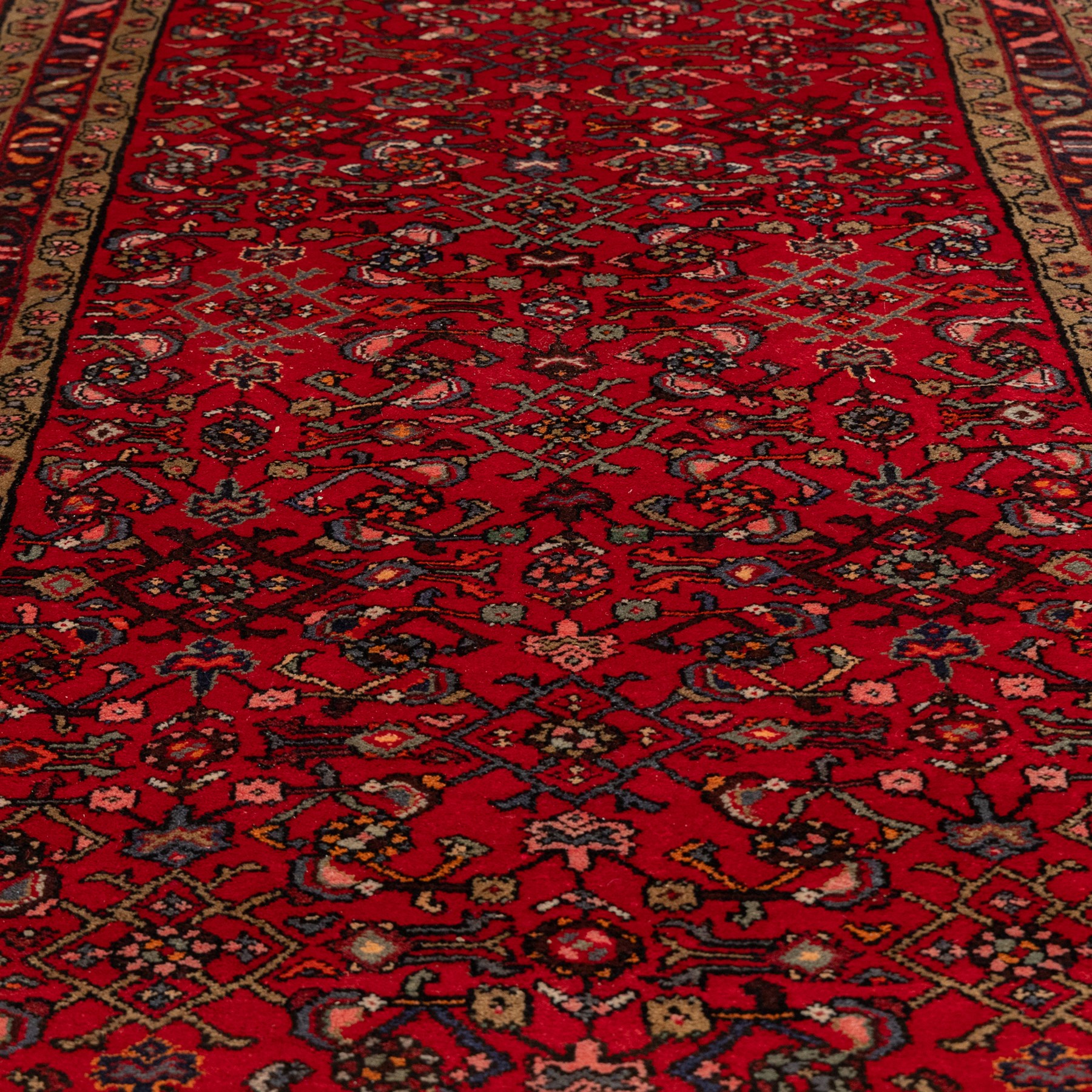 North West Persian runner, the red field decorated with an all-over Herati pattern of diamond lattice motifs, rosettes and serrated leaves, ivory floral spandrels, enclosed by an indigo palmette border and narrow floral guard bands