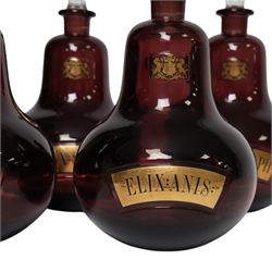 Set of four 20th century Royal Pharmaceutical Society amethyst glass bottles, of bellied form with clear cut glass spire stopper, each body bearing gilt label in Latin: ELIX:THYM:, ELIX:CAMPH:, ELIX:ANIS: and ELIX:SENN:, and gilt Royal Pharmaceutical Society crest to neck, H25cm

Provenance: From the collection of the family of Peter Green, a practising pharmacist whose career spanned the mid to late 20th century. During his professional life he managed pharmacies in Yeovil, Somerset, and later Selles Chemist in Filey, North Yorkshire, before purchasing and running his own business, Peter Green Pharmacy, located in the Market Place, Malton. The bottles were displayed as part of the traditional shop fittings in both the Filey and Malton pharmacies and were retained as part of his collection.