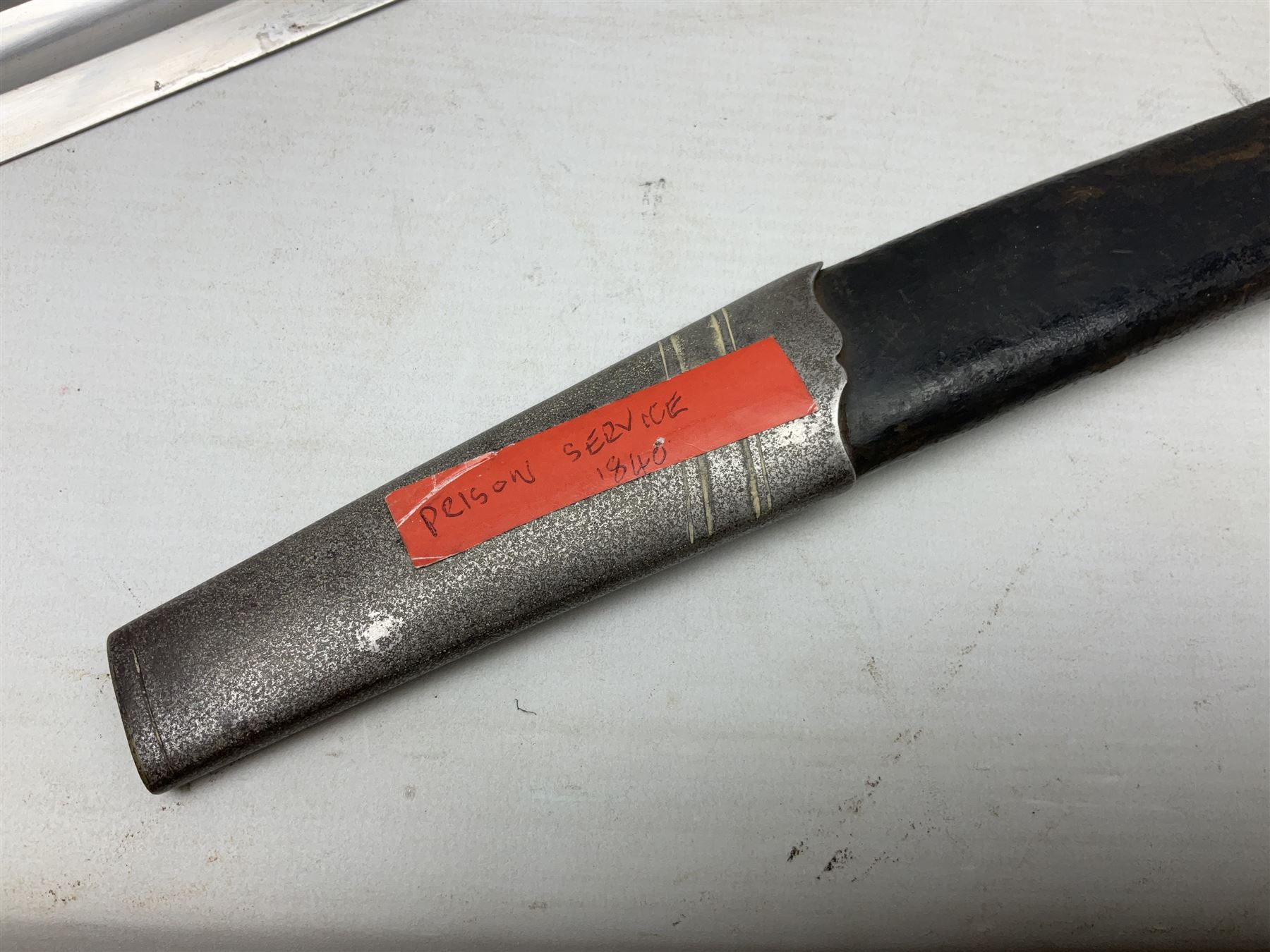 Mid-19th century Custom’s officer/Constabulary sidearm, with plain 60.5cm slightly curving fullered blade double edged at tip,  steel knucklebow and downswept quillon, stepped pommel and ribbed fishskin grip; in leather covered scabbard with steel locket, frog stud and chape L76cm overall