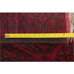 Afghan crimson ground Bokhara rug, the field with three rows of repeating Gul motifs, within six concentric guard bands decorated with repeating geometric patterns