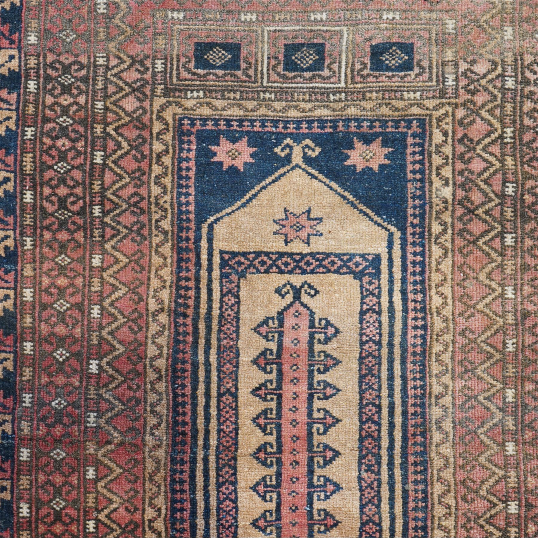 Persian Baluch style prayer rug,  hand-knotted wool rug, central mihrab design with geometric hooked motifs, corners with medallions, outlined in dark blue, with a stepped arch with hanging lamp motif at the top, main border on dark blue ground with alternating hooked and stepped motifs, guard borders with repeating diamond and chevron pattern 