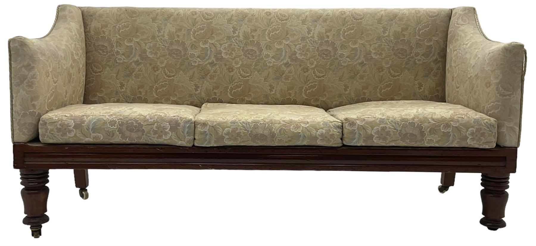 Victorian mahogany framed three-seat settee, upholstered in floral pattern fabric, on turned feet with brass and ceramic castors 