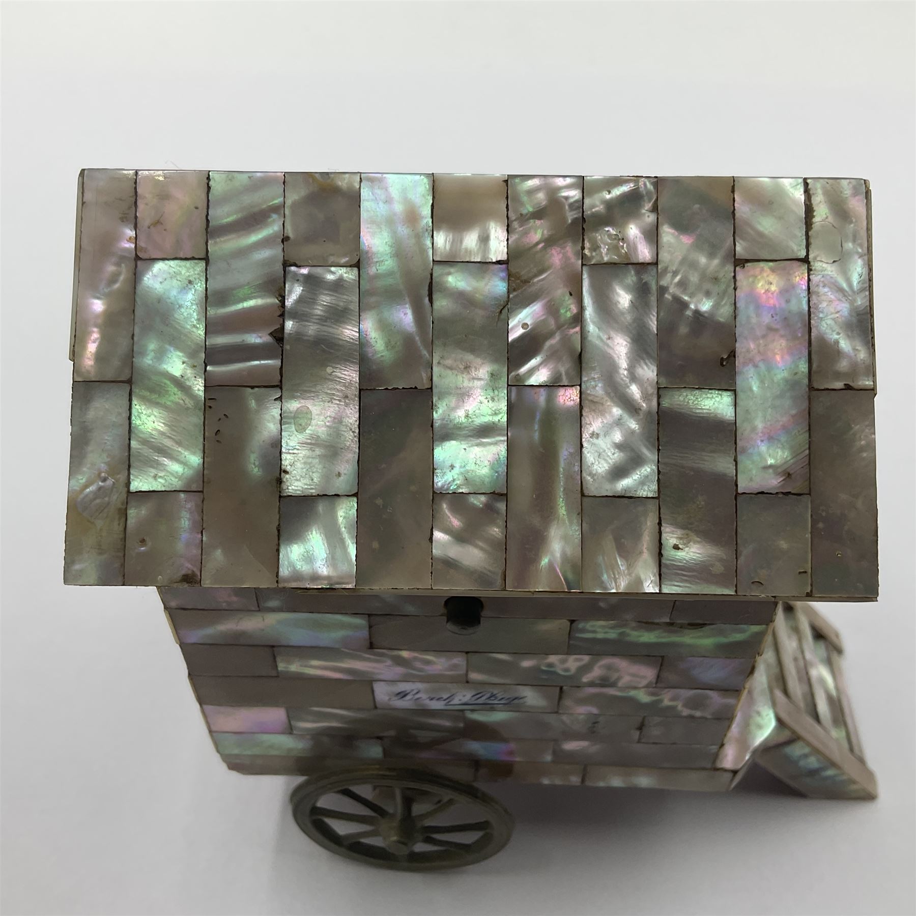 19th century French souvenir jewellery casket in the form of a bathing machine, having mother of pearl panelled tiled effect body, hinged roof/cover revealing a blue silk fitted interior with cushioned base, two silvered metal wheels, abalone shell door and mother of pearl steps, inscribed 'Berck Plage' in blue, H12cm, W13cm 