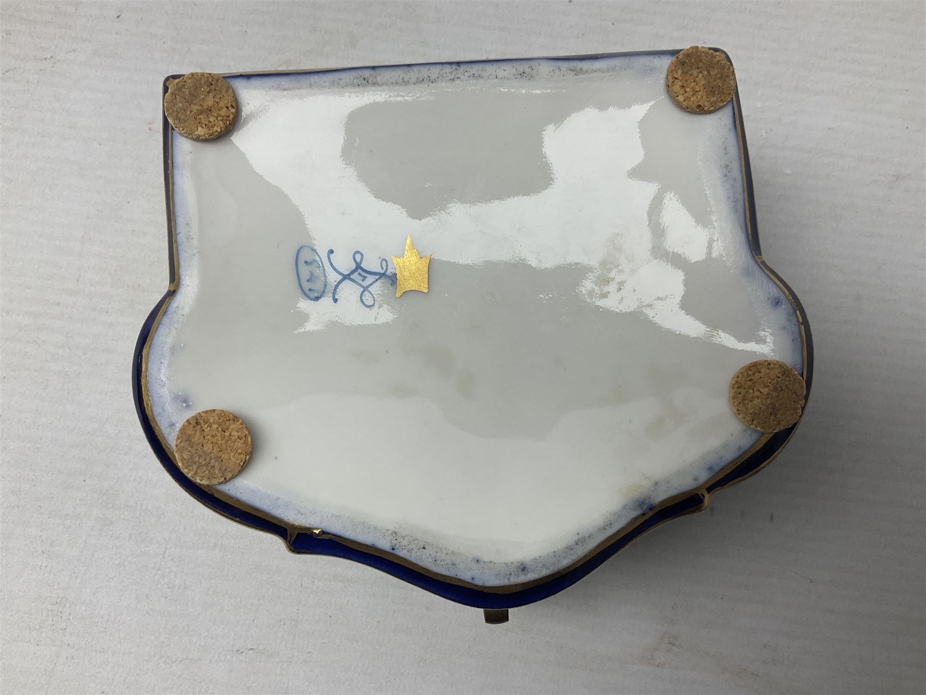 Sevres style late 19th/early 20th century trinket box decorated in the rococo style, the shaped cover painted with an 18th century courting couple in a garden scene opening to reveal the interior painted with floral sprays, the conforming body with a painted panel of floral decoration, all reserved upon cobalt blue ground with foliate gilt borders, with interlaced L's mark beneath, L12cm H6cm