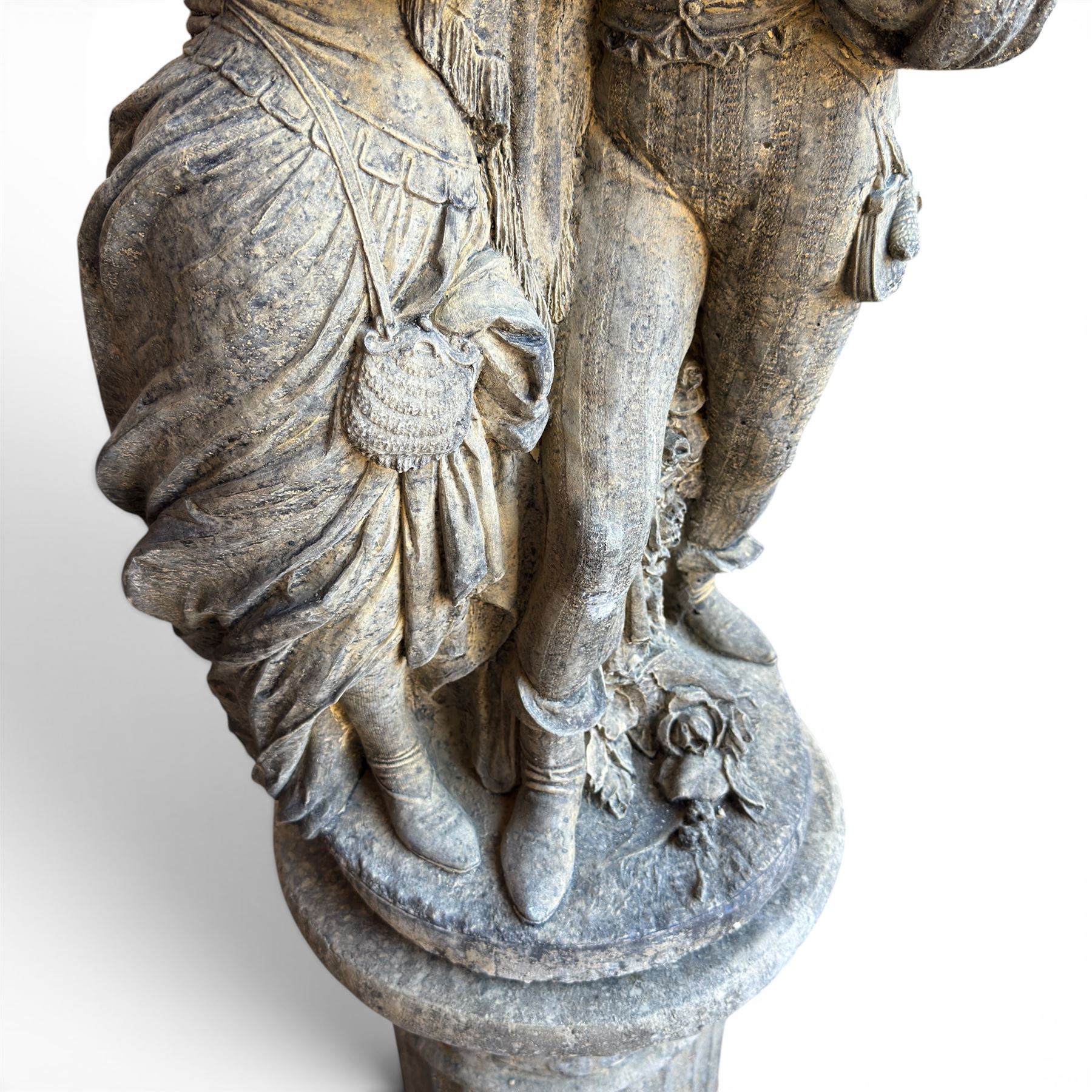 Composite garden statue group of Romeo and Juliet embracing, the couple adorned in Medieval dress standing on a naturalistic base with fallen flowers, raised on a Neoclassical fluted pedestal with Anthemion leaf motifs
