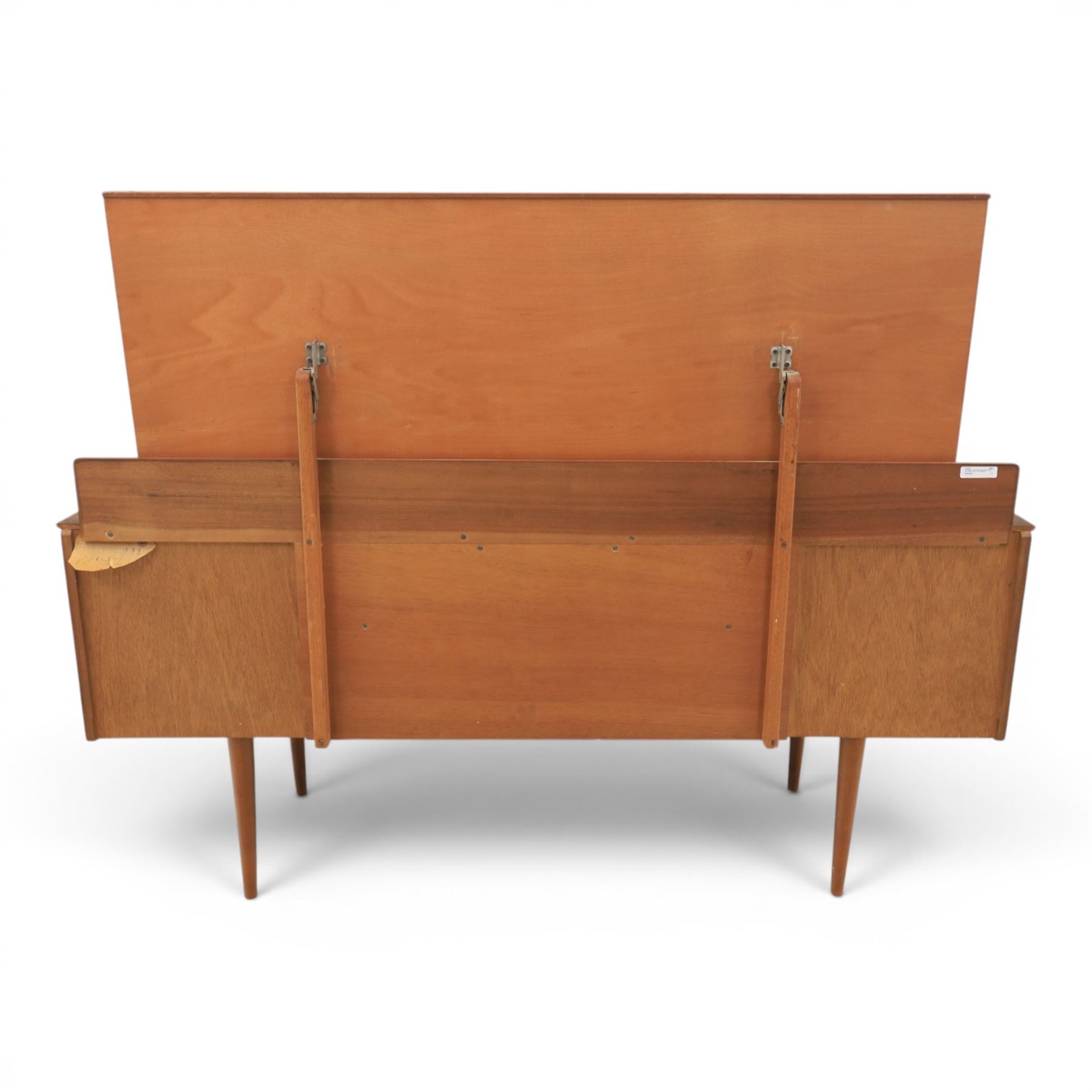 Austinsuite - mid 20th century teak headboard with bedside cabinets and matching  mirrored dressing table, the headboard with floating single drawer bedsides raised on a single tapering support, the dressing table with attached tilting mirror, above rectangular top with kneehole and two banks of two drawers, raised on tapering supports

Headboard H 84cm, D 40cm, W 229cm, W between bedsides 151cm 
Dressing table H 113cm D 44cm, W 149cm, H to underside of dresser 61cm