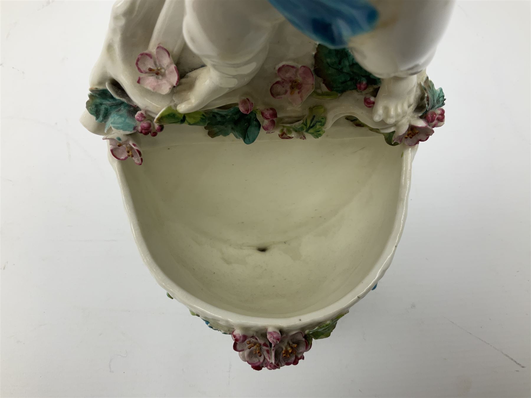 Victorian wall pocket by Moore Brothers retailed by T.Goode modelled as a semi nude white glaze cherub with turquoise ribbon, with encrusted floral decoration, the reverse stamped ‘T.Goode & Co.’, H32cm